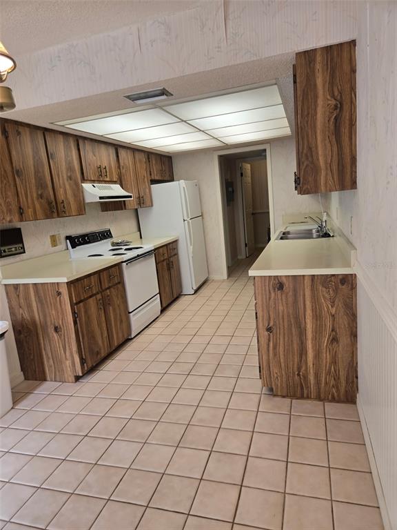 A kitchen features wood-grain cabinets, light countertops, white appliances, and tiled flooring — 4343 NW 80TH AVENUE UNIT 2, OCALA, FL