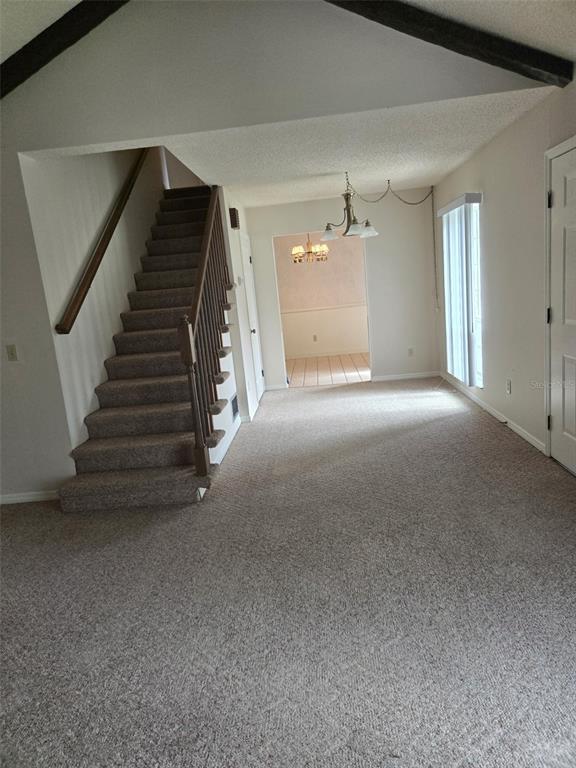 A carpeted living room features a staircase with a wooden railing and a vaulted ceiling — 4343 NW 80TH AVENUE UNIT 2, OCALA, FL