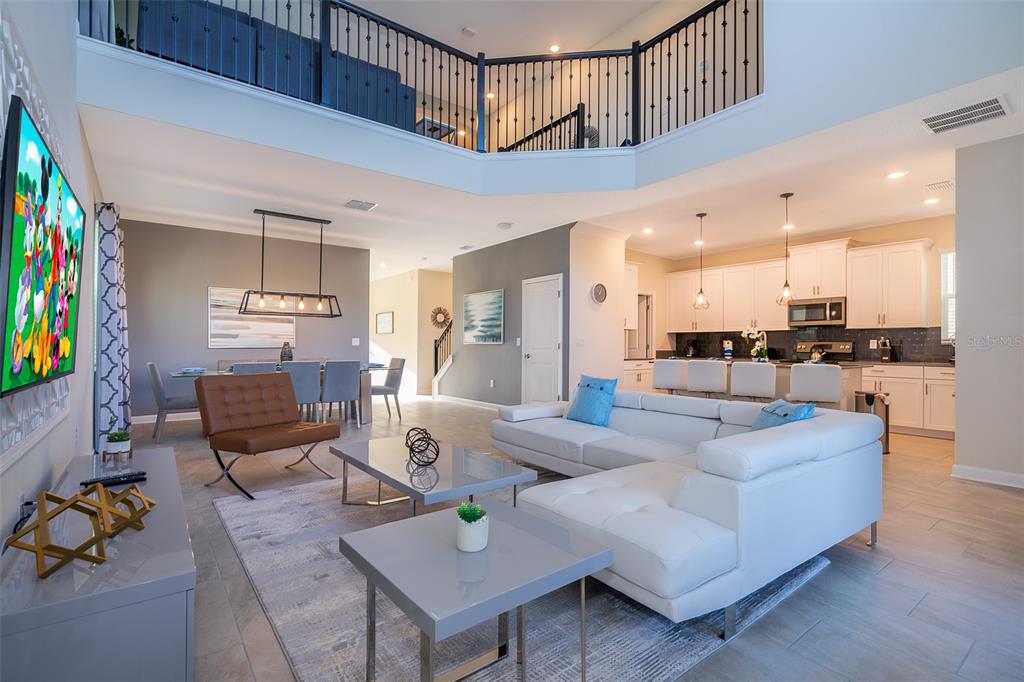 An open-concept living room and kitchen featuring white cabinetry, a sectional sofa, and lofted ceilings — 800 STICKS STREET, DAVENPORT, FL