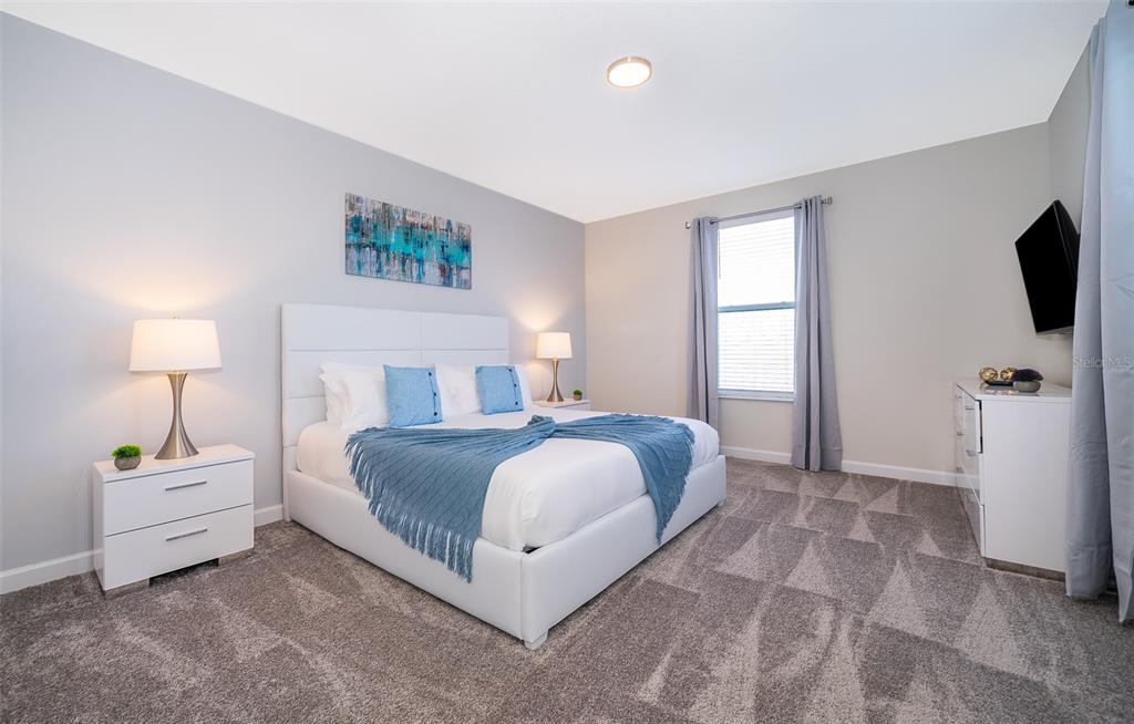 A bedroom features a white bed, two nightstands, a dresser with a television, and carpet — 800 STICKS STREET, DAVENPORT, FL
