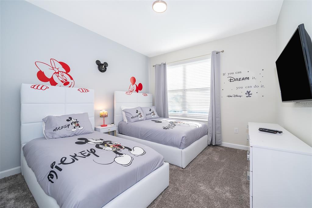 A bedroom features two beds with Mickey Mouse bedding, white headboards, and Disney-themed wall decals — 800 STICKS STREET, DAVENPORT, FL