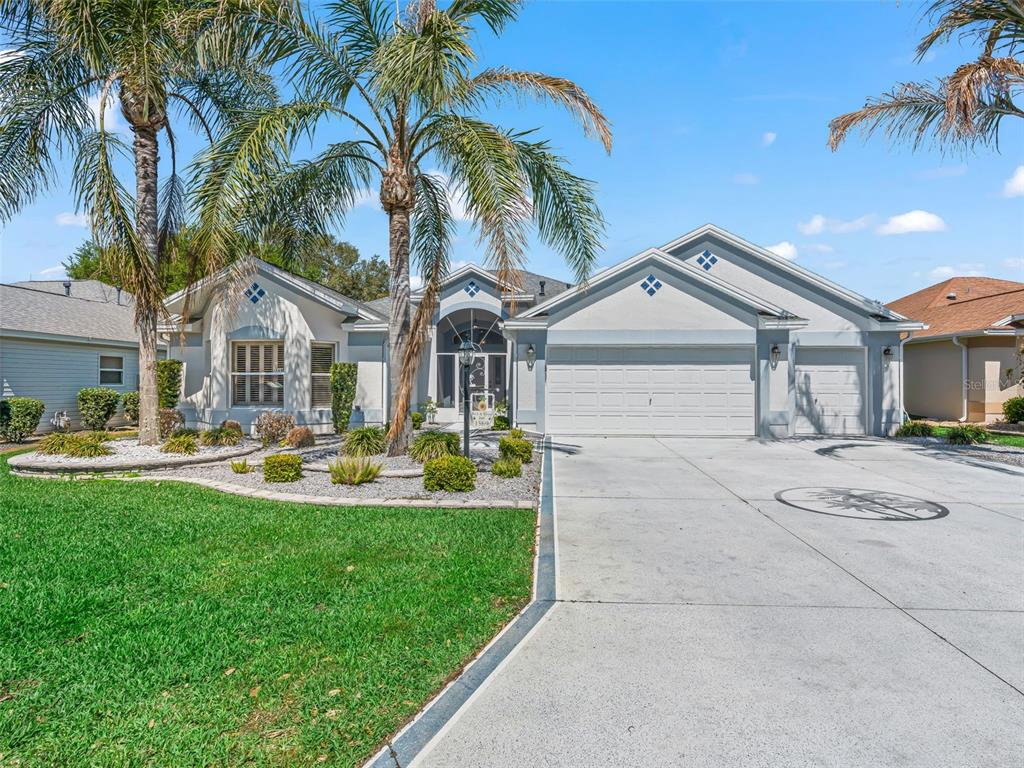 A single-story house with a light-colored exterior, a three-car garage, and palm trees — 1569 OLAR COURT, THE VILLAGES, FL