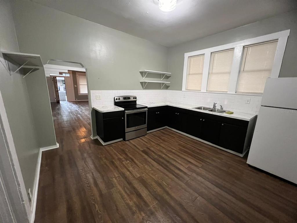 A kitchen features black cabinets, white countertops, stainless steel appliances, and wood-look flooring — 3021 SANCHEZ STREET, TAMPA, FL
