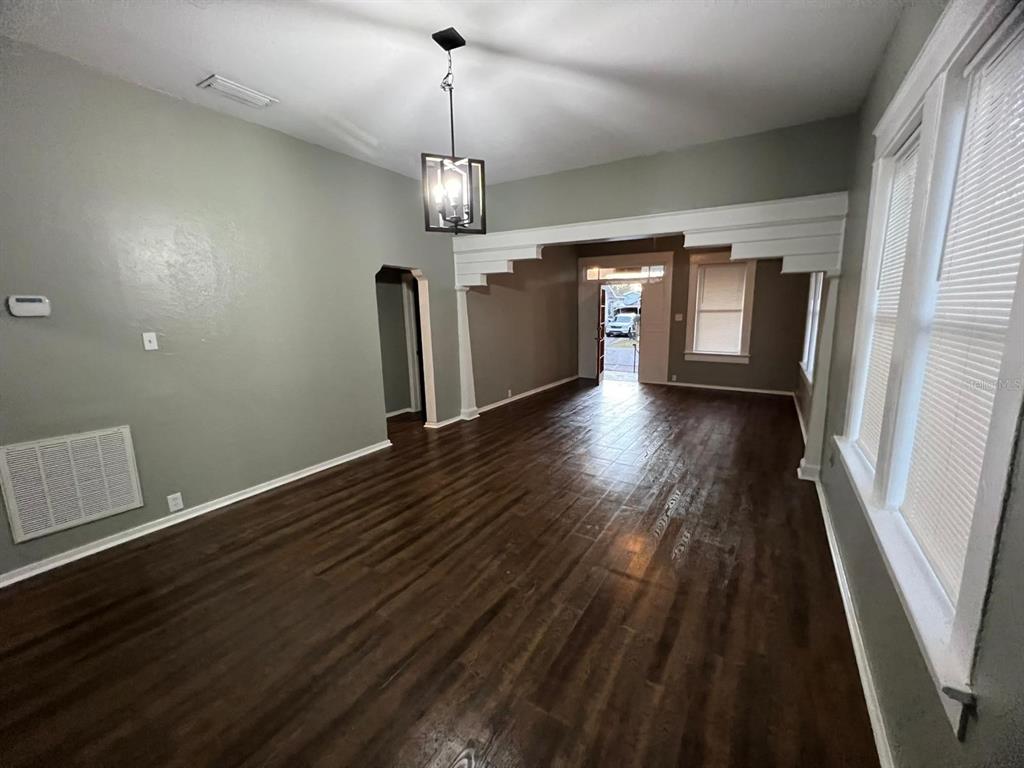 An empty living room features dark wood-look flooring, gray walls, and a decorative white archway — 3021 SANCHEZ STREET, TAMPA, FL