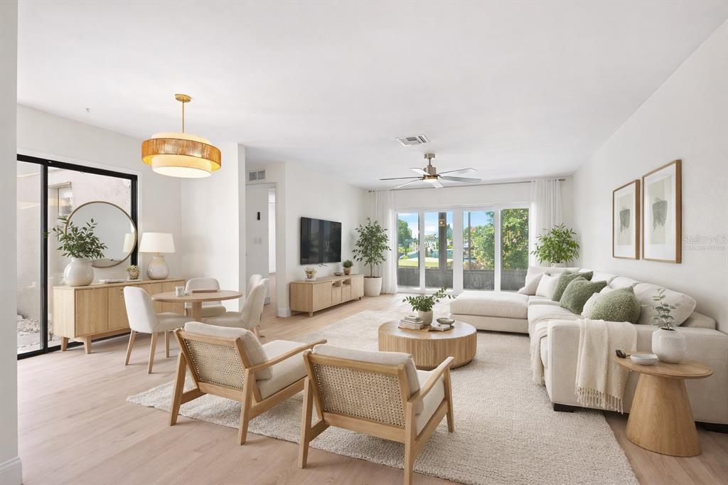 A bright, open-concept living and dining area features light wood floors, neutral furniture, and large windows — 4448 MARINE PARKWAY, NEW PORT RICHEY, FL