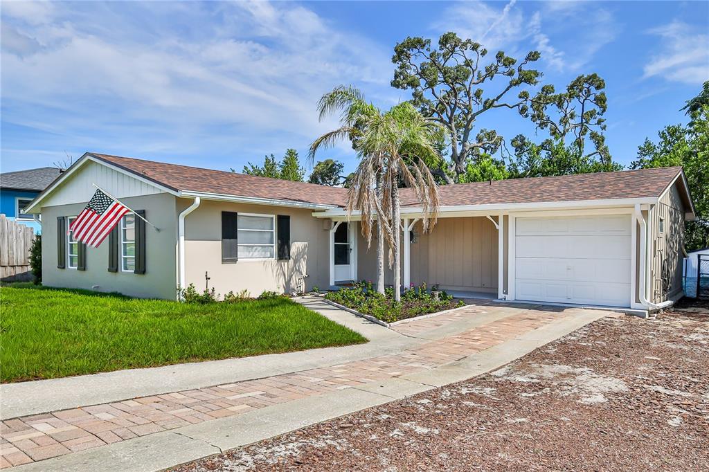 A single-story house with a tan exterior, a brick driveway, and an attached garage — 7163 FIRESIDE STREET, SPRING HILL, FL