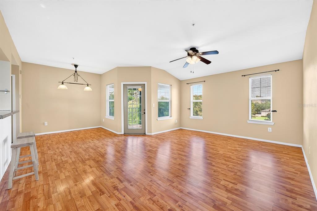 An empty living room features light tan walls, wood-look flooring, a ceiling fan, and windows — 420 SUMMIT RIDGE PLACE UNIT 316, LONGWOOD, FL