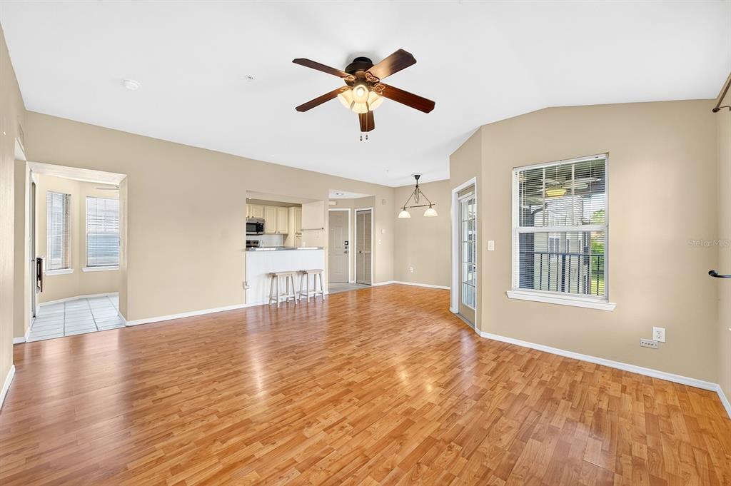 A living room with wood flooring, a ceiling fan, and an adjacent kitchen area — 420 SUMMIT RIDGE PLACE UNIT 316, LONGWOOD, FL
