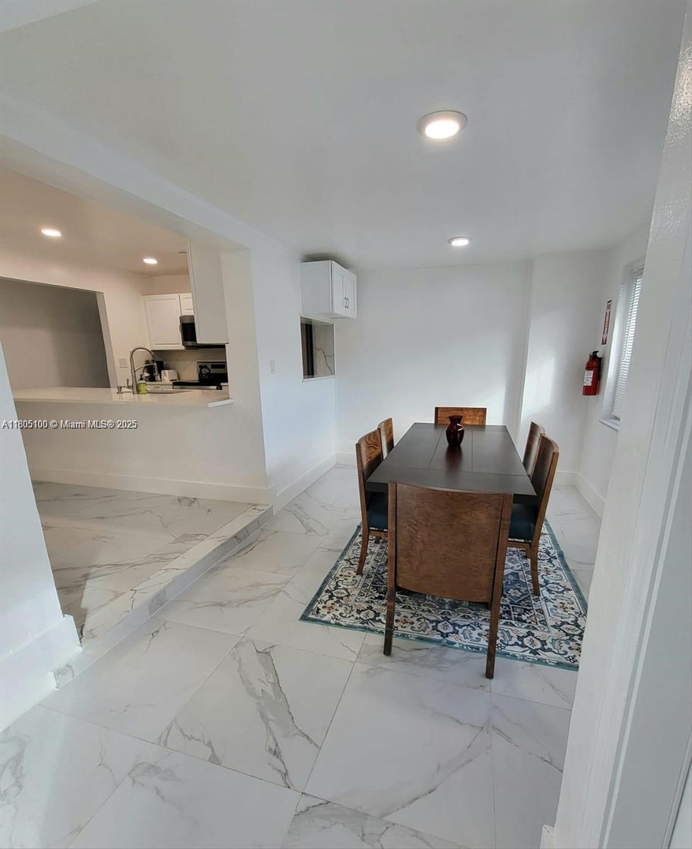 A dining area with a dark wood table and chairs sits on a patterned rug — FORT LAUDERDALE, FL