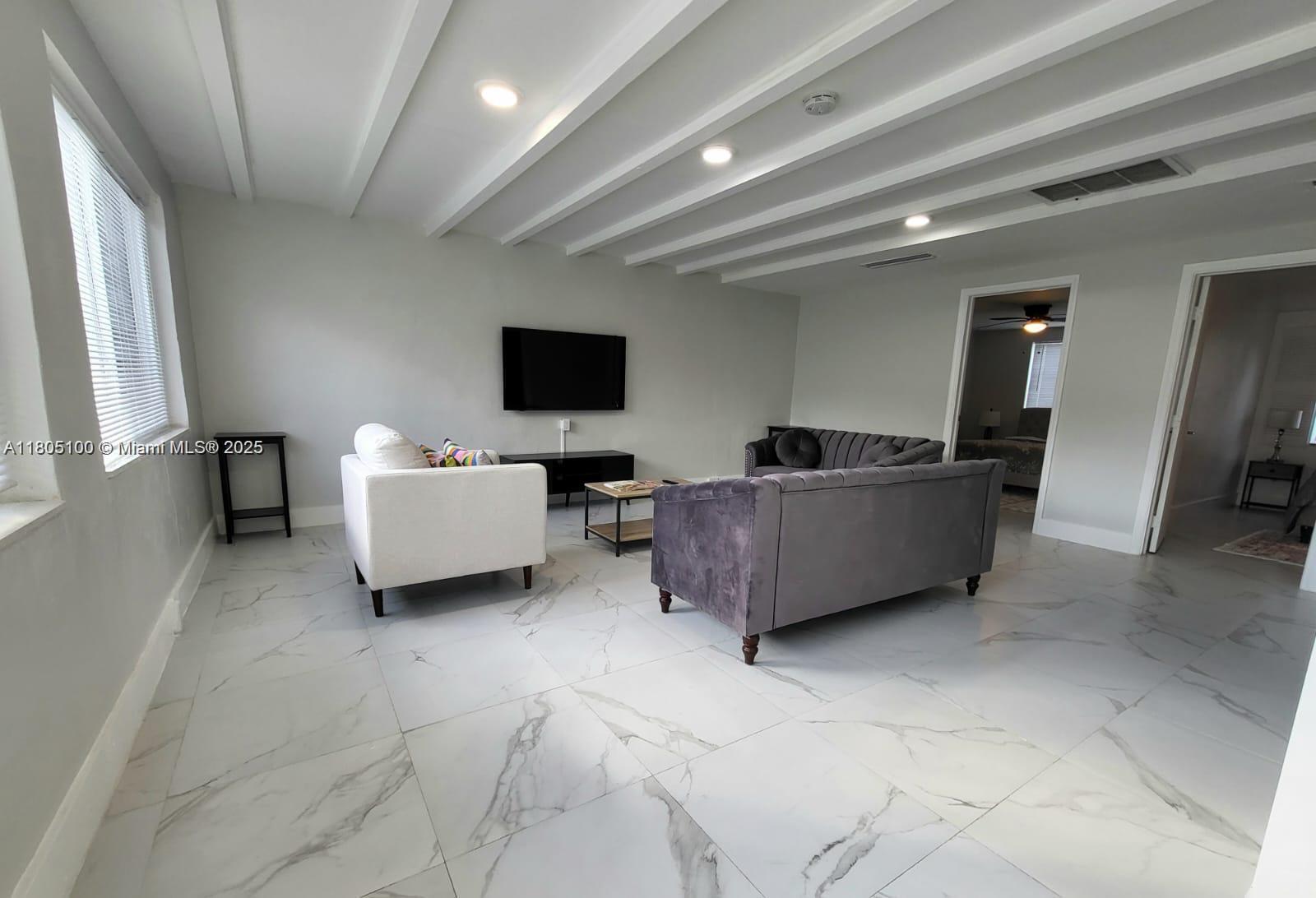 A living room features white marble-look tile floors, a coffered ceiling, and two sofas — FORT LAUDERDALE, FL