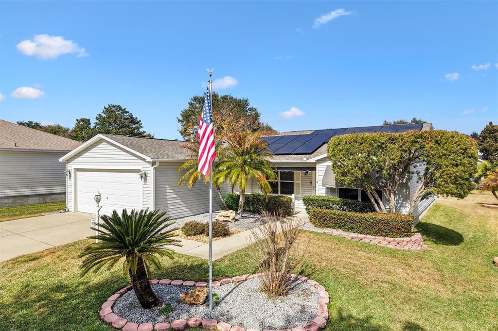 A single-story house with a garage, solar panels, and an American flag in the yard — 9711 SE 171ST ARGYLL STREET, THE VILLAGES, FL