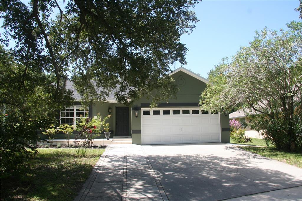 A single-story house with olive green siding, a white garage door, and a concrete driveway — 2680 LAKE JACKSON CIRCLE, APOPKA, FL