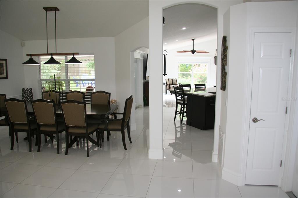 A dining room with a dark table and chairs leads into a kitchen with an island — 2680 LAKE JACKSON CIRCLE, APOPKA, FL