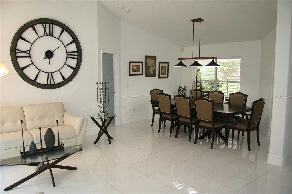 A dining room and living area with white tile floors, a large wall clock, and furniture — 2680 LAKE JACKSON CIRCLE, APOPKA, FL