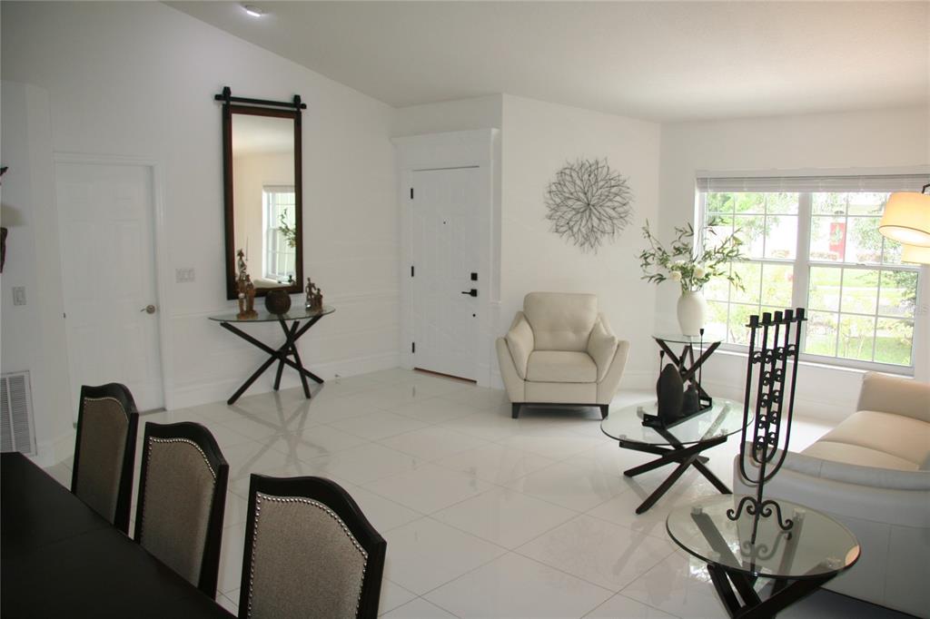 A bright living room features white tile floors, a glass coffee table, and a white armchair — 2680 LAKE JACKSON CIRCLE, APOPKA, FL