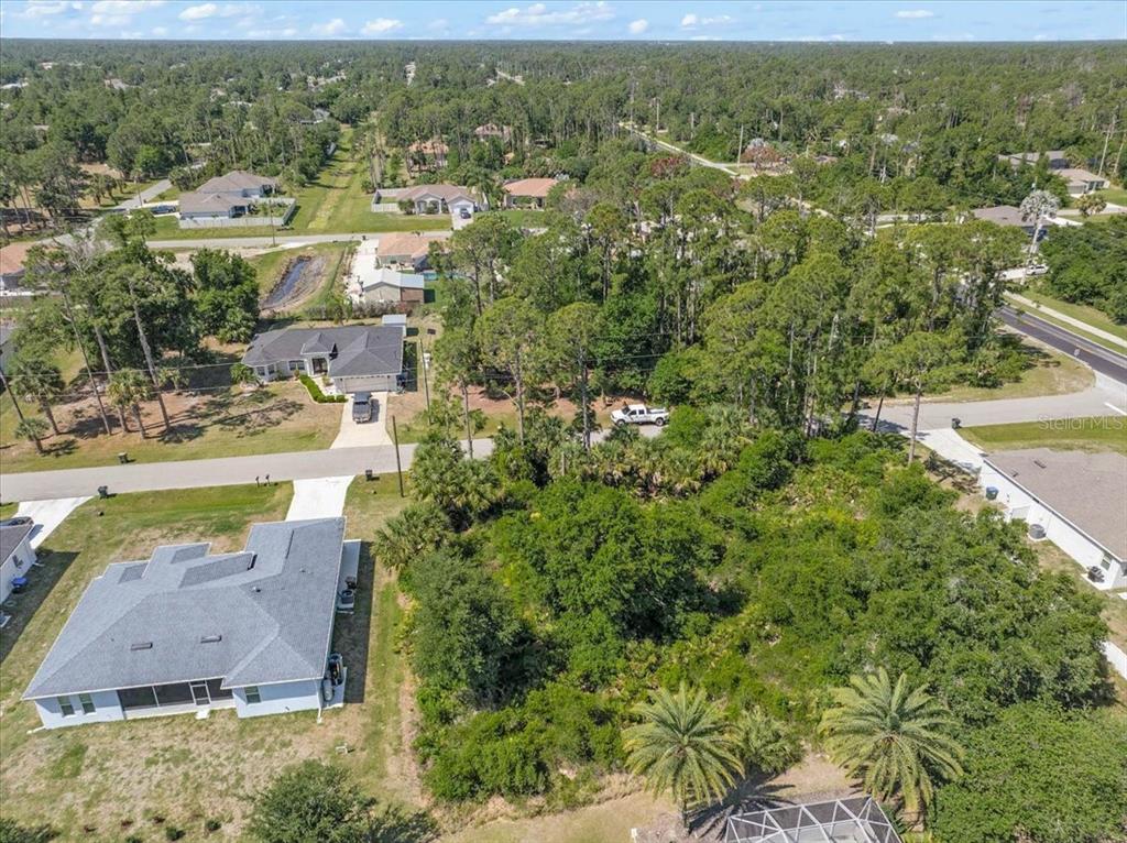 An aerial view shows a vacant, wooded lot situated between two residential houses — WOODWARD AVENUE, NORTH PORT, FL