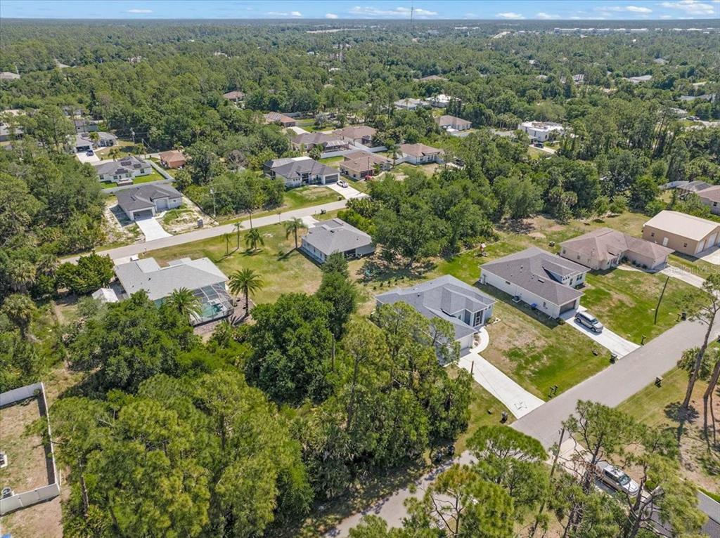 An aerial view shows several single-family homes surrounded by dense trees and green lawns — WOODWARD AVENUE, NORTH PORT, FL
