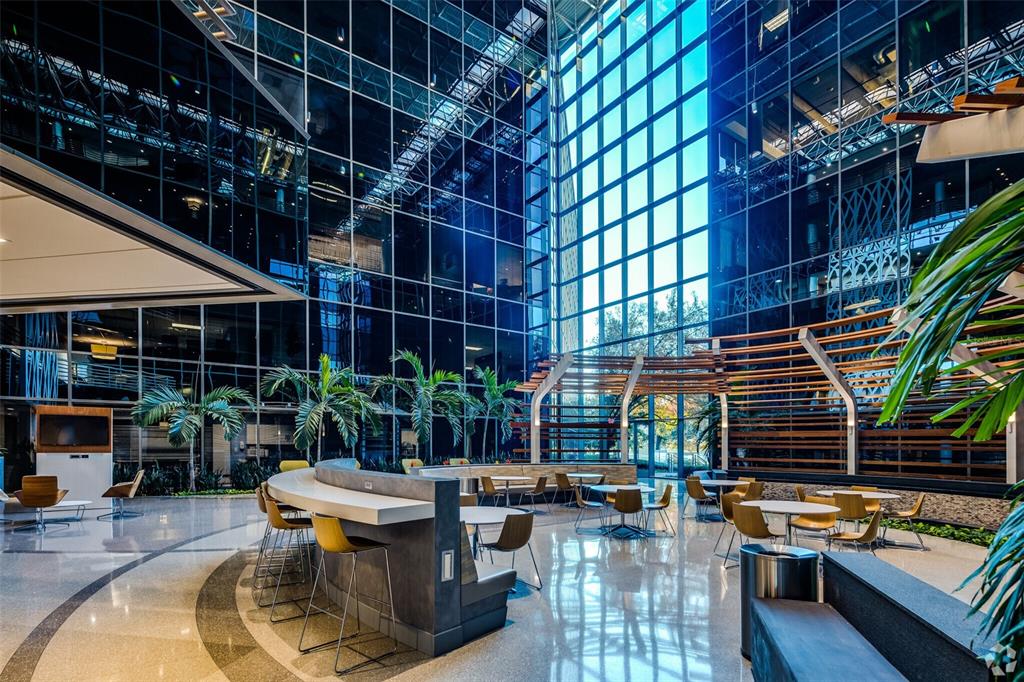 A modern office building lobby features a curved bar, seating areas, and floor-to-ceiling glass walls — 225 E ROBINSON STREET, ORLANDO, FL