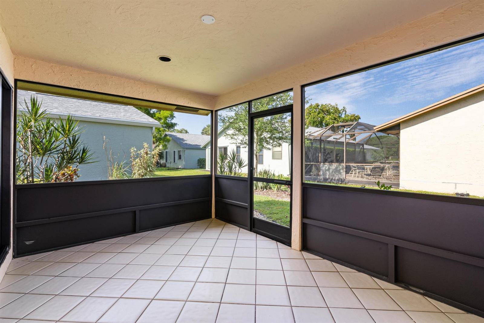 A screened-in porch with tiled flooring, black metal framing, and views of neighboring houses — 786 NW 31st Avenue, Delray Beach FL 33445, DELRAY BEACH, FL