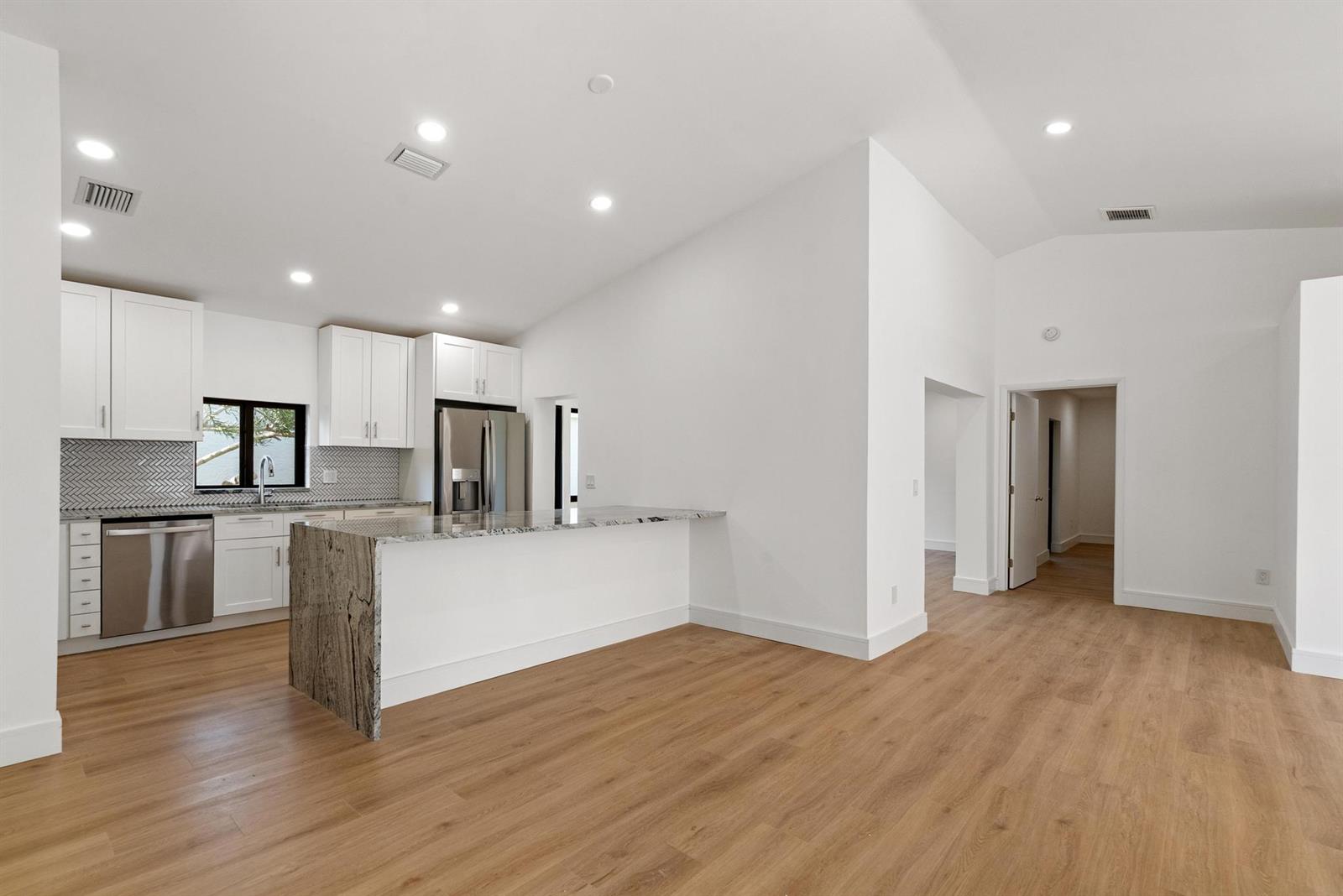 A modern kitchen features white cabinets, granite countertops, and light wood flooring — 786 NW 31st Avenue, Delray Beach FL 33445, DELRAY BEACH, FL