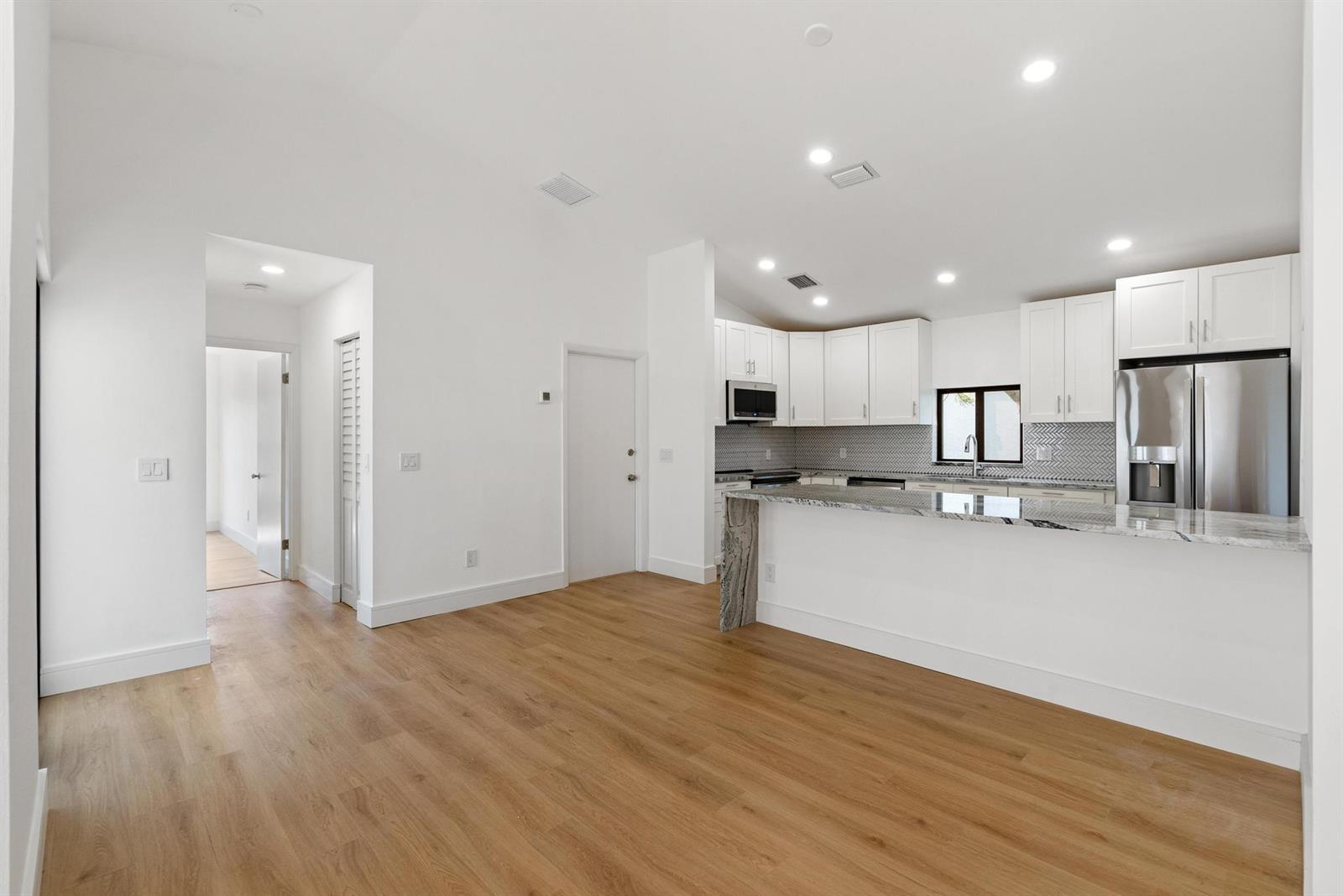 A bright kitchen with white cabinets, granite countertops, and light wood flooring — 786 NW 31st Avenue, Delray Beach FL 33445, DELRAY BEACH, FL