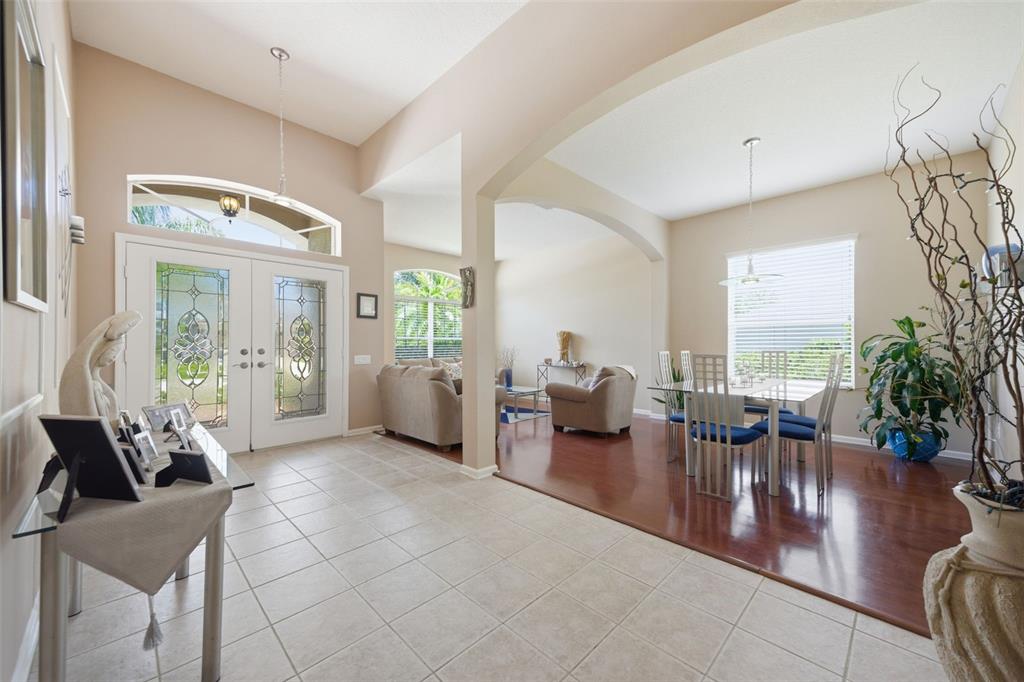 A bright entryway with tile flooring leads to a dining area with hardwood floors — 25946 RISEN STAR DRIVE, WESLEY CHAPEL, FL