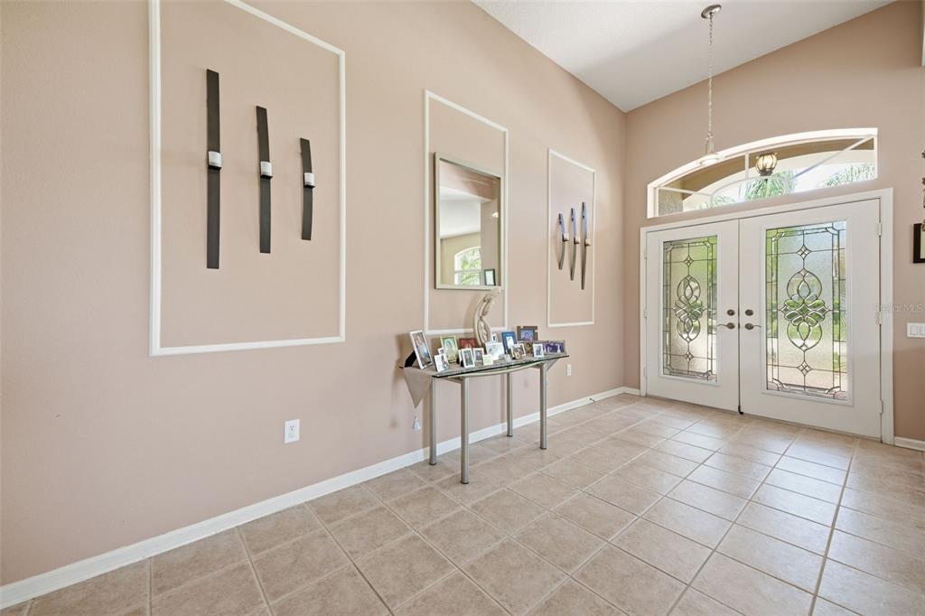 An entryway features tile flooring, a glass console table, wall molding, and double glass doors — 25946 RISEN STAR DRIVE, WESLEY CHAPEL, FL