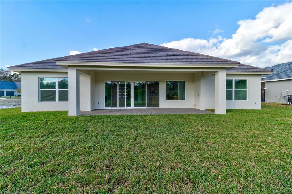 The exterior rear view of a single-story house features a covered patio and lawn — 74 NEW LEATHERWOOD DRIVE, PALM COAST, FL