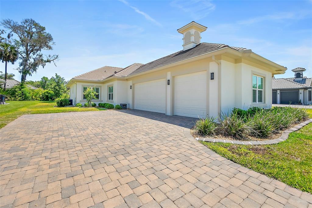 A paved driveway leads to the two-car garage of a light-colored stucco house — 74 NEW LEATHERWOOD DRIVE, PALM COAST, FL