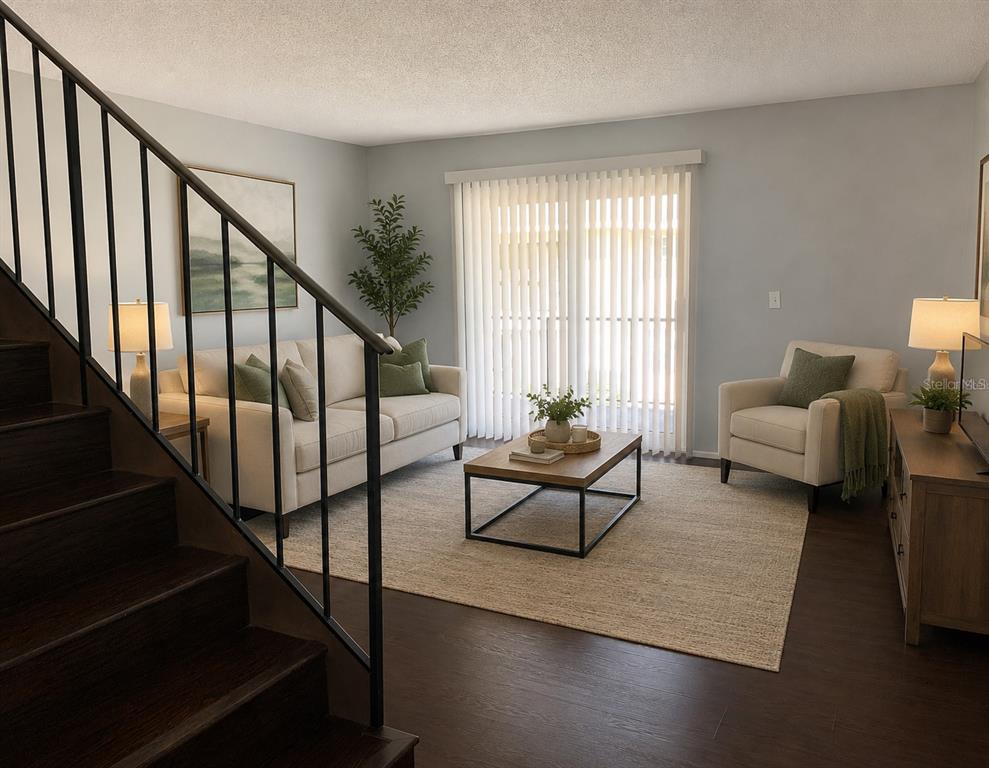 A living room with dark wood stairs, a beige sofa, an armchair, and sliding glass doors — 14402 REUTER STRASSE CIRCLE UNIT #2, TAMPA, FL