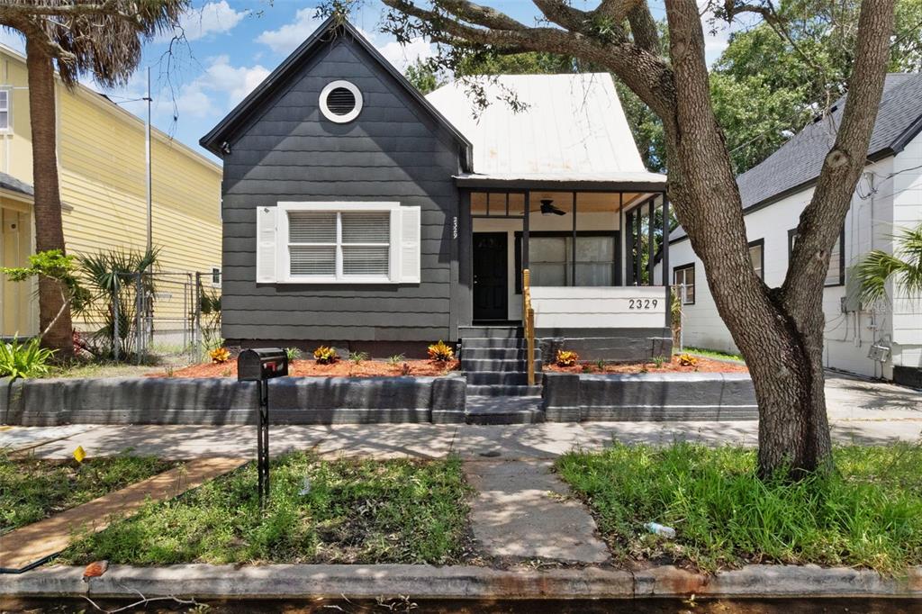 A dark gray house with a white roof and a front porch sits behind a wall — 2329 W BEACH STREET, TAMPA, FL