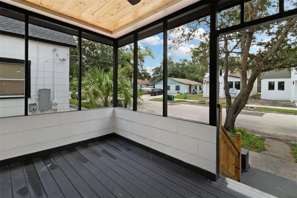 A screened-in porch features dark wood flooring, white paneled walls, and a natural wood ceiling — 2329 W BEACH STREET, TAMPA, FL