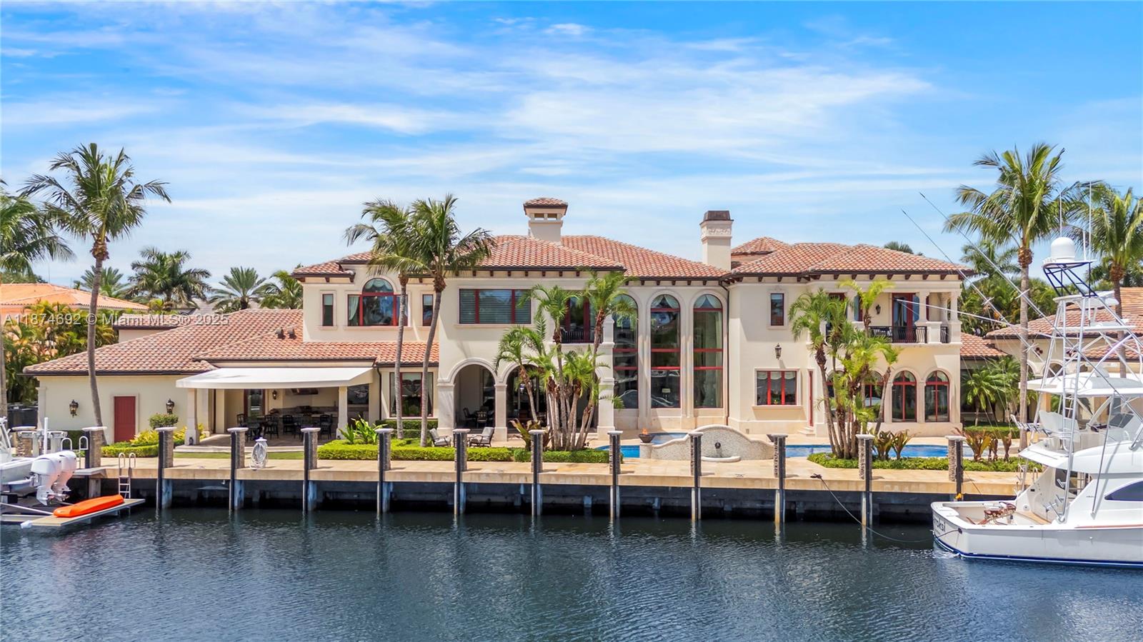 A large waterfront Mediterranean-style house features a tiled roof, arched windows, and a private dock — 700 Osprey Point Cir, Boca Raton FL 33431, BOCA RATON, FL