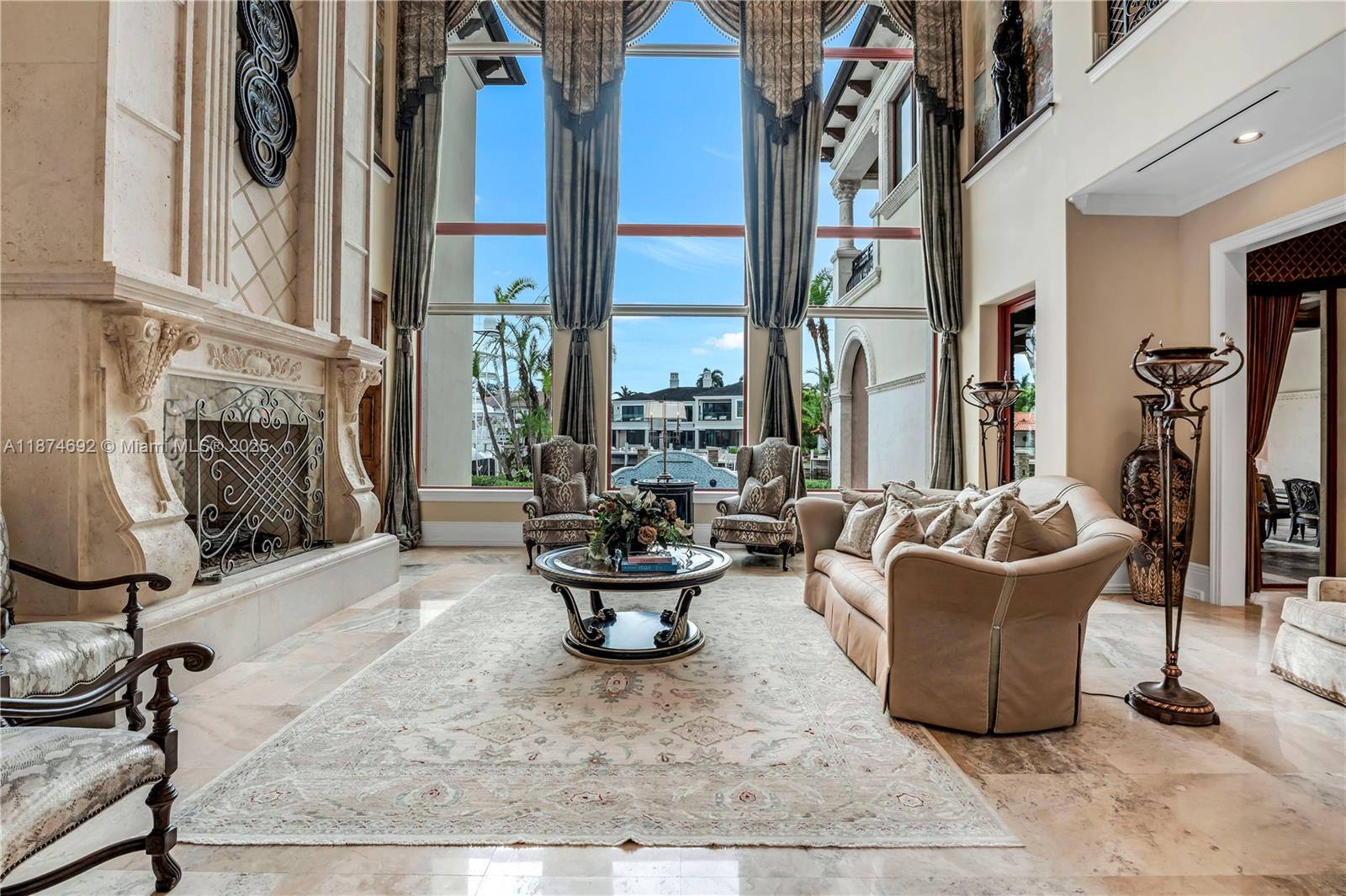 A grand living room features a massive stone fireplace, floor-to-ceiling windows, and marble flooring — 700 Osprey Point Cir, Boca Raton FL 33431, BOCA RATON, FL