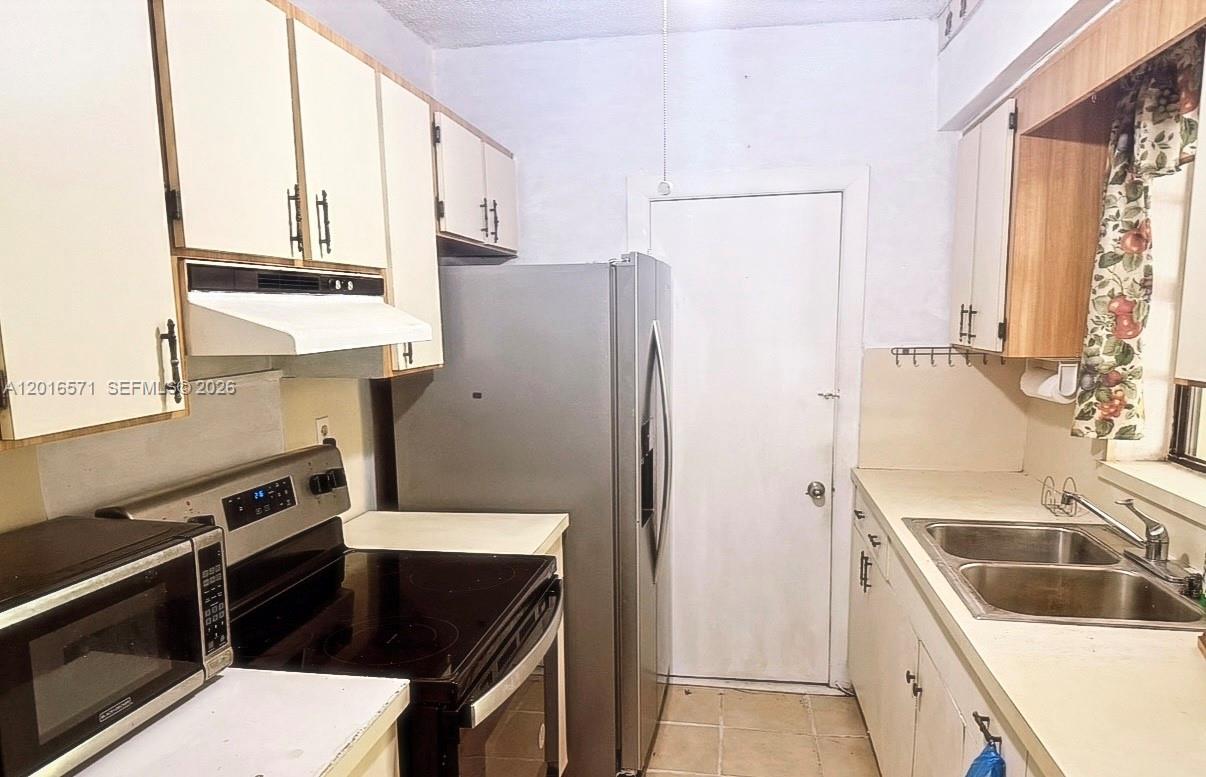 A kitchen features white cabinets, stainless steel appliances, and a double-basin sink — 50 E 44th St, Hialeah FL 33013, HIALEAH, FL