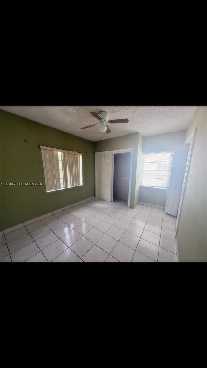 A bedroom with white tile flooring, green walls, a ceiling fan, and two windows — 50 E 44th St, Hialeah FL 33013, HIALEAH, FL