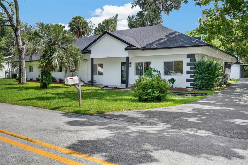 A white single-story house with a dark roof, black trim, and a paved driveway — 730 W UNIVERSITY AVENUE, DELAND, FL