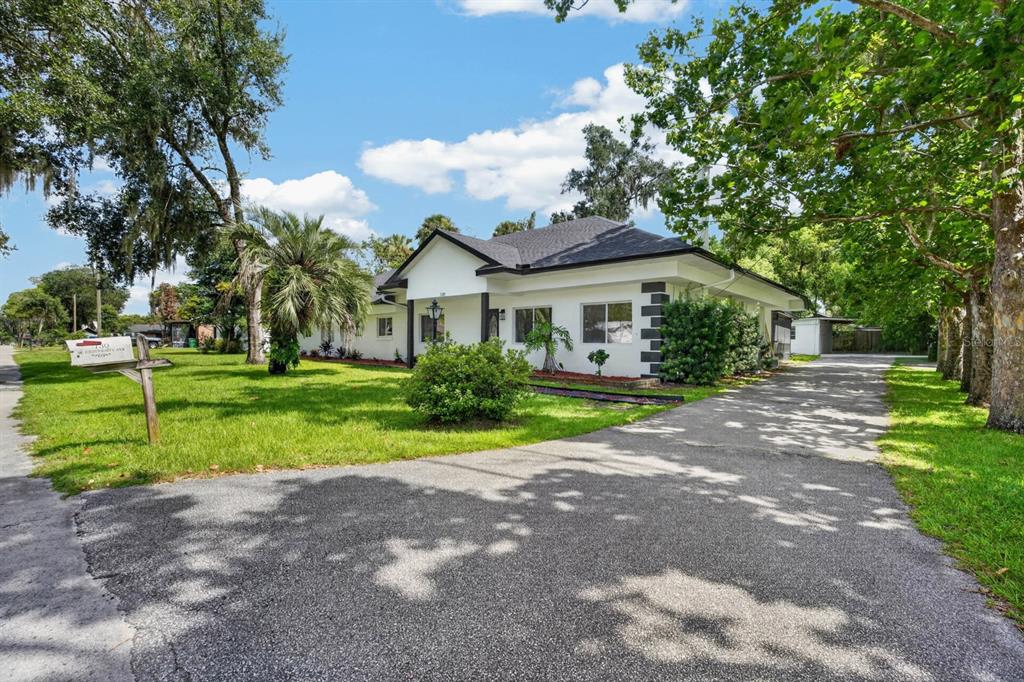 A white, single-story house with a dark roof and a long driveway sits on a lawn — 730 W UNIVERSITY AVENUE, DELAND, FL