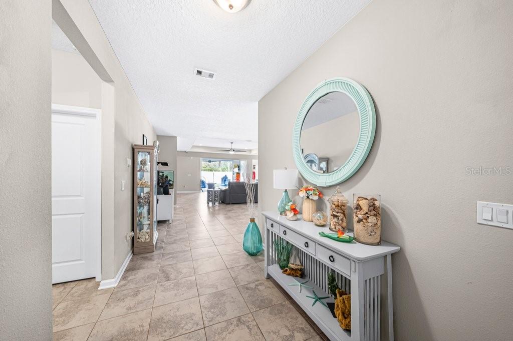 A tiled entryway features a console table with decor, a round mirror, and a hallway view — 338 WILLOW LAKE DRIVE, ST AUGUSTINE, FL