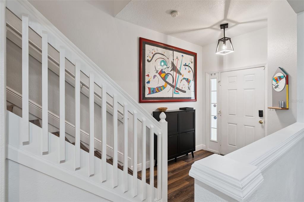 An entryway features a white staircase, a black storage cabinet, and a framed abstract painting — 2521 GALLIANO CIRCLE, WINTER PARK, FL
