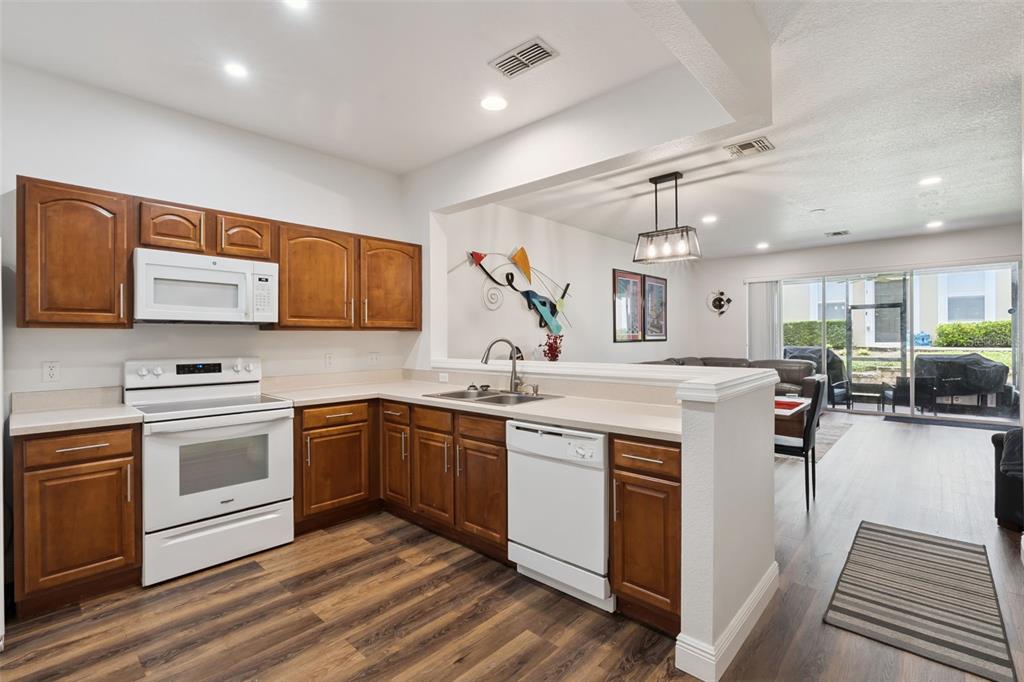 A kitchen with wood cabinets, white appliances, and a breakfast bar overlooking a living area — 2521 GALLIANO CIRCLE, WINTER PARK, FL