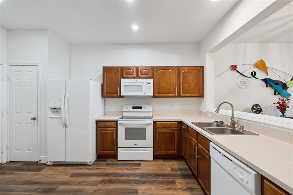 A kitchen features wood cabinets, white appliances, light countertops, and wood-look flooring — 2521 GALLIANO CIRCLE, WINTER PARK, FL