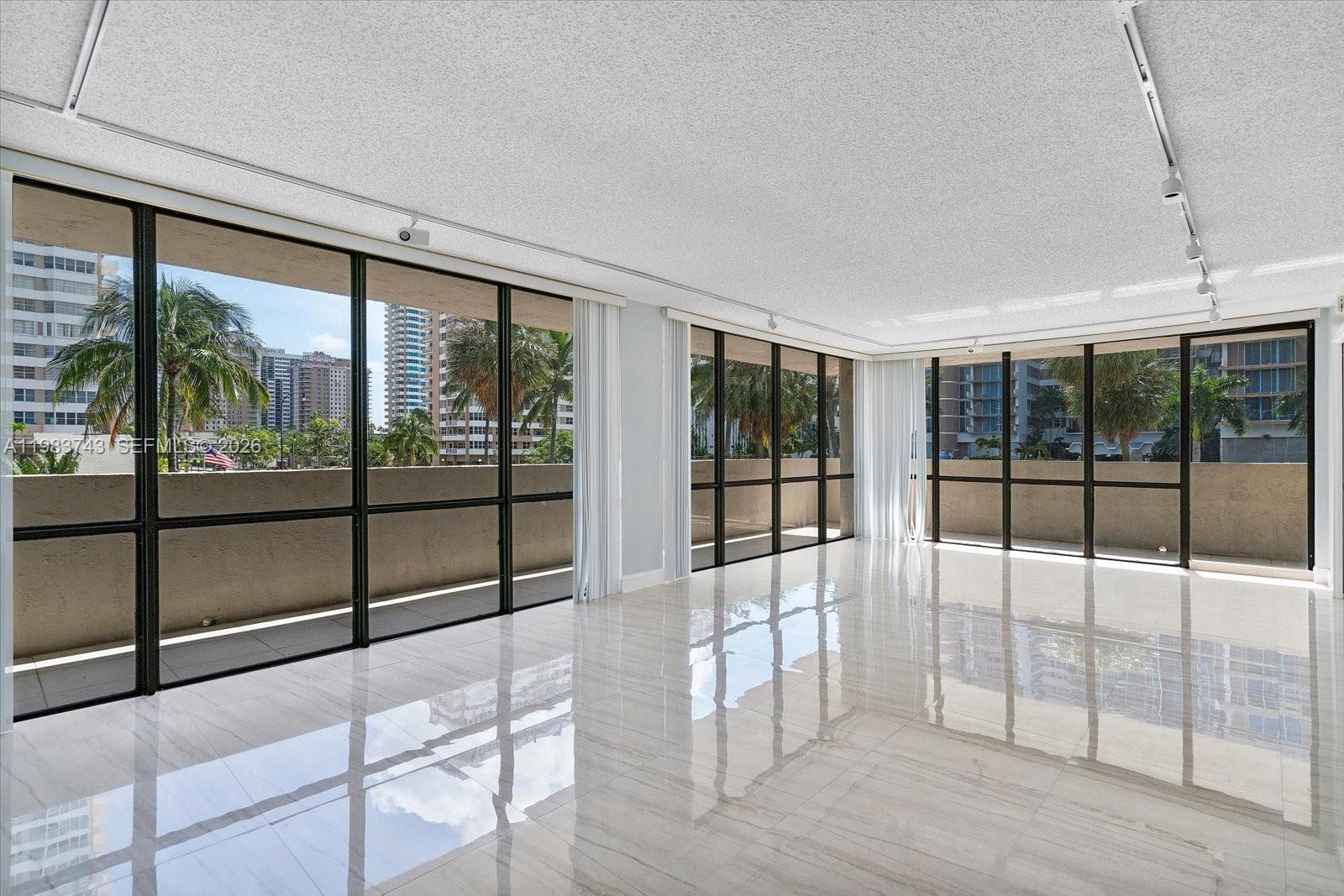 An empty room with white tile floors, a textured ceiling, and floor-to-ceiling windows — 2049 S Ocean Dr # 210, Hallandale Beach FL 33009, HALLANDALE BEACH, FL