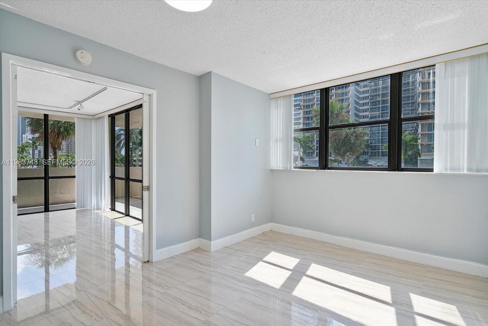 A bright room with light-colored tile flooring, pale blue walls, and large windows — 2049 S Ocean Dr # 210, Hallandale Beach FL 33009, HALLANDALE BEACH, FL