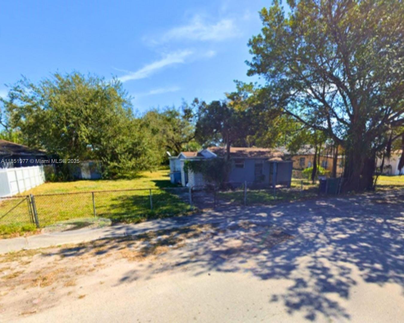 A small, single-story house sits on a grassy lot behind a chain-link fence — 4501 NW 33rd Ave, Miami FL 33142, MIAMI, FL