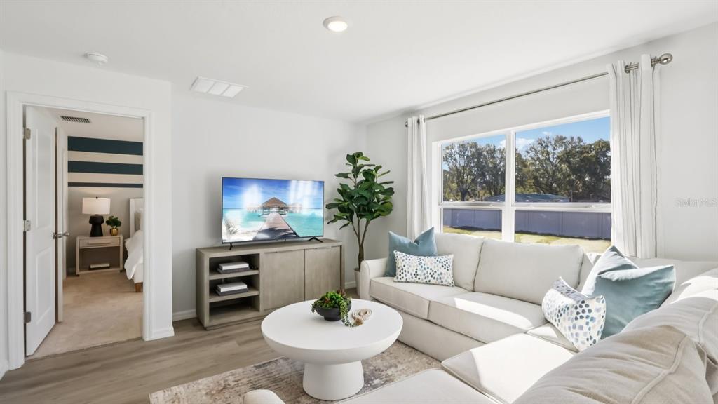 A living room features a white sectional sofa, a round coffee table, and a television — 1013 GUM SPRING COURT, RUSKIN, FL