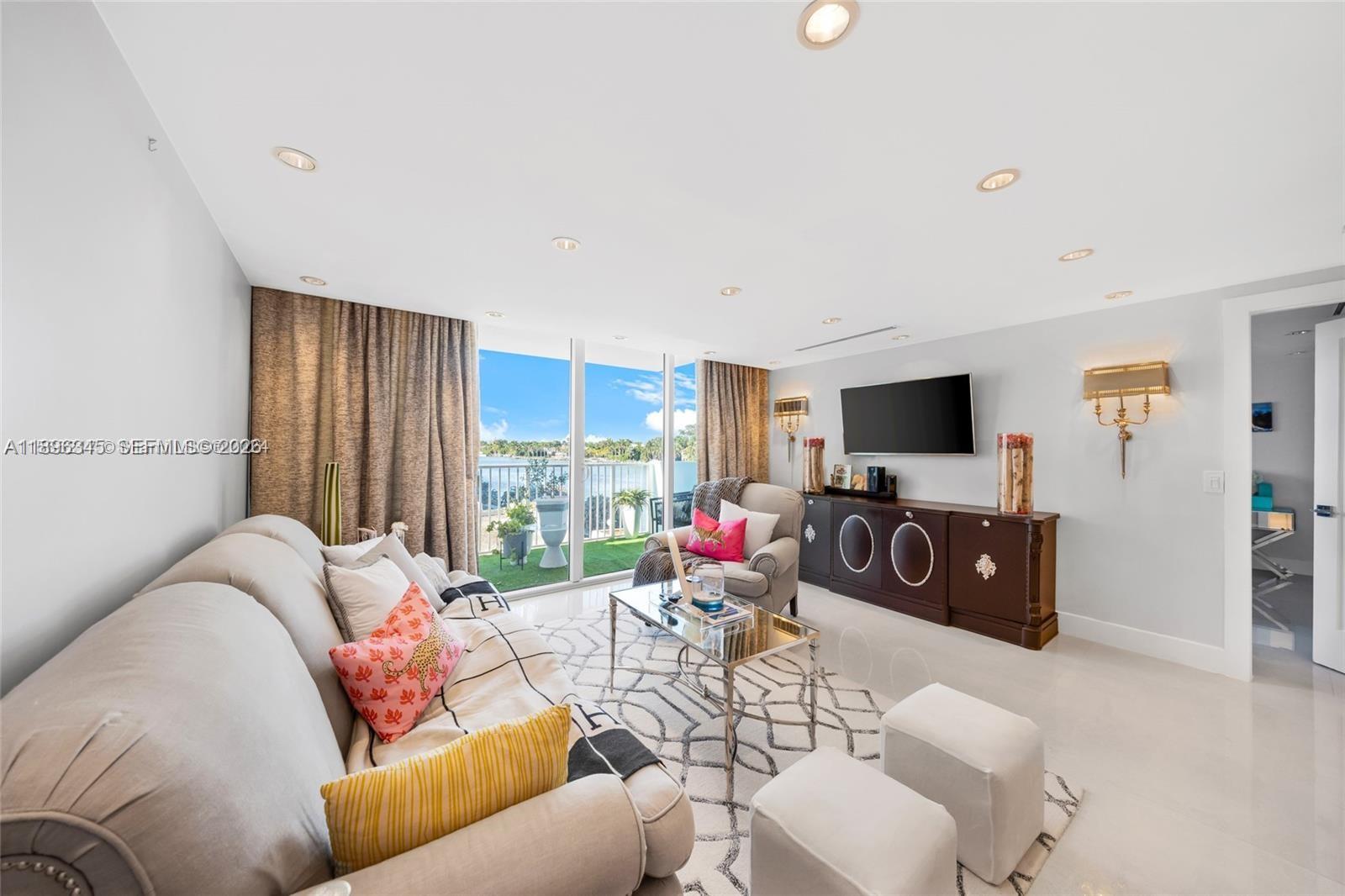 A living room features a sofa, armchairs, a coffee table, and a balcony with water views — 5838 Collins Ave # 2F, Miami Beach FL 33140, MIAMI BEACH, FL