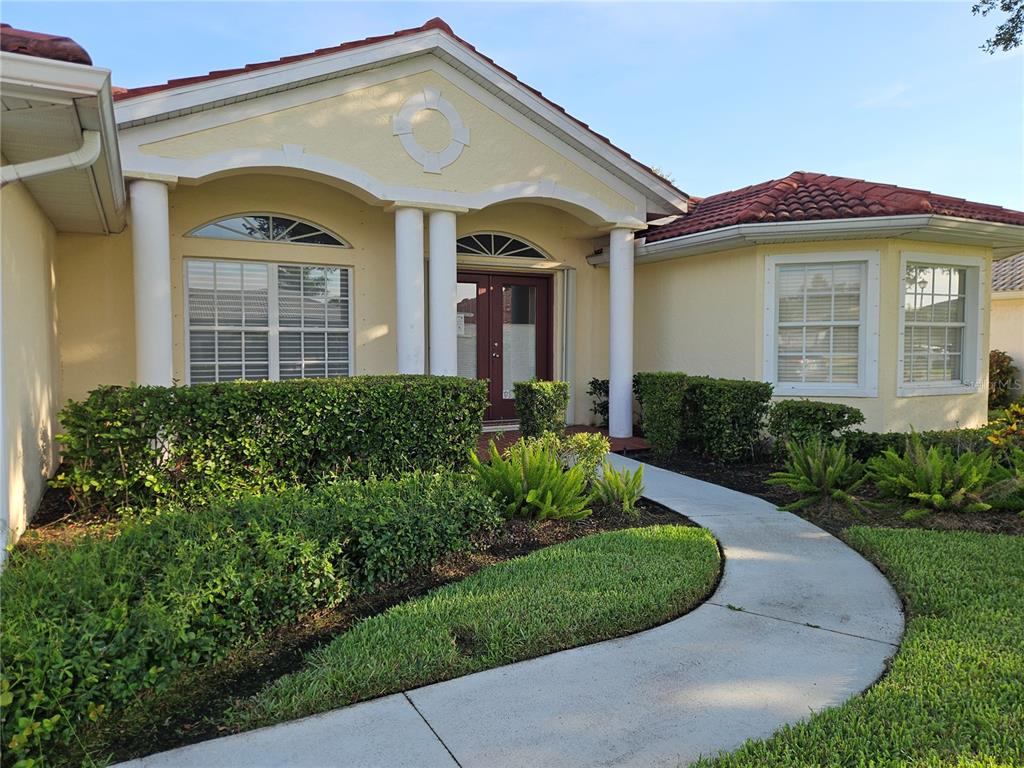 A single-story house with a curved walkway, white columns, and a red tile roof — 6628 DEERING CIRCLE, SARASOTA, FL
