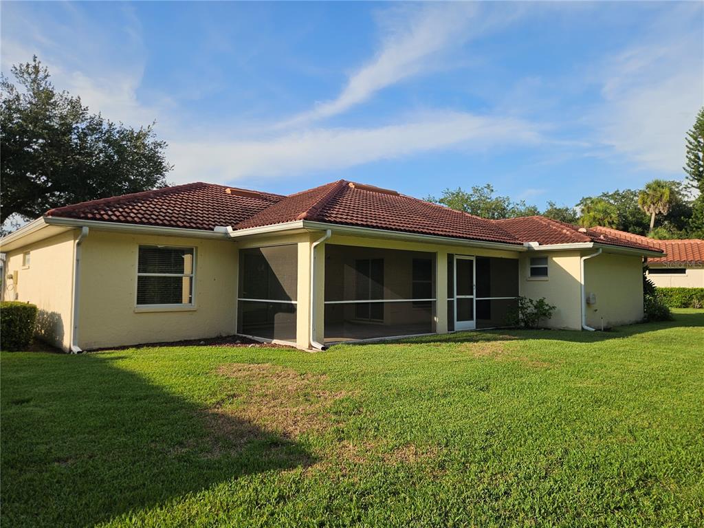 The rear exterior of a single-story house features a screened-in lanai and a tiled roof — 6628 DEERING CIRCLE, SARASOTA, FL