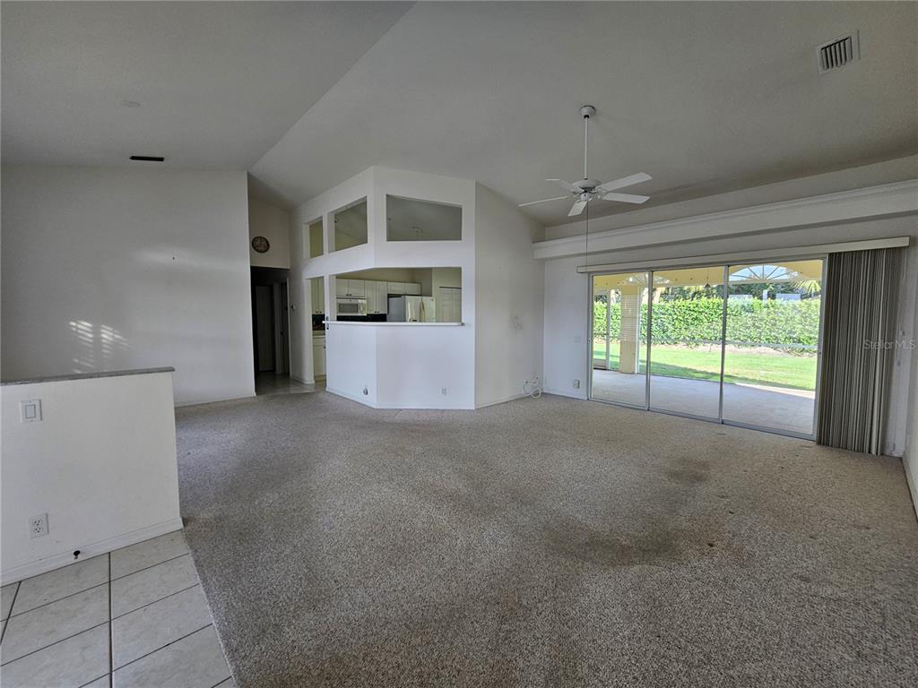 A spacious living room features beige carpeting, a vaulted ceiling, and sliding glass patio doors — 6628 DEERING CIRCLE, SARASOTA, FL